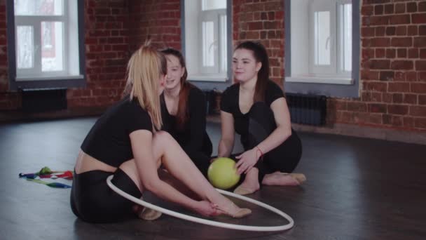 체조 - 세 명의 곡예하는 여자들이 공을 가지고 바닥에 앉아 있고 체조 연습과 말하기 위해 입을 벌리고 있는 모습 — 비디오