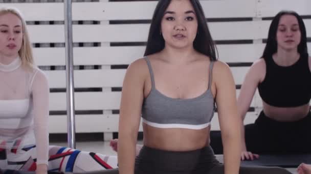 Trening fitness - grupa kobiet rozgrzewająca się - siedząca na podłodze i pochylona do przodu — Wideo stockowe