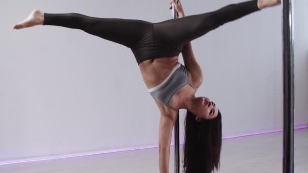 Фітнес-тренування - жінка, що стоїть догори ногами, тримається біля полюса і стоїть однією рукою на підлозі — стокове відео