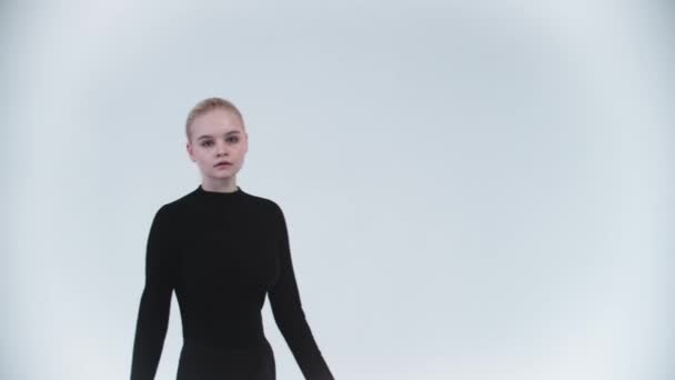 Gymnastics - young woman raising up her leg against her body and holding it - looking in the camera — Stock Video