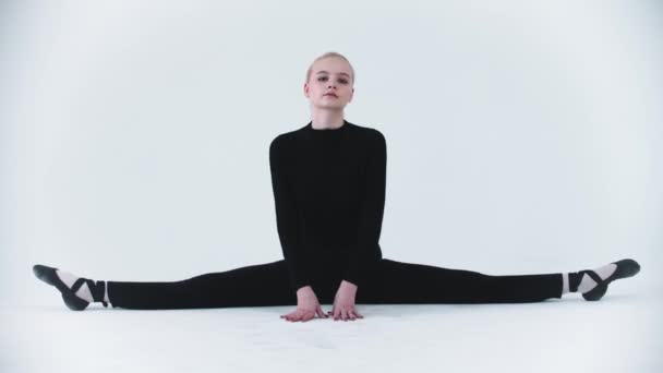 Gymnastique - jeune femme assise dans une fente et penchée sur les côtés - regardant dans la caméra — Video