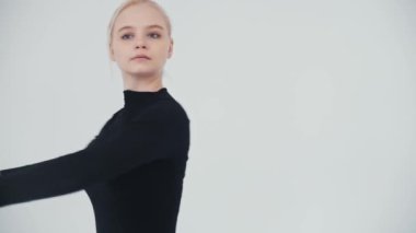 Genç sarışın balerin stüdyoda dans ediyor.