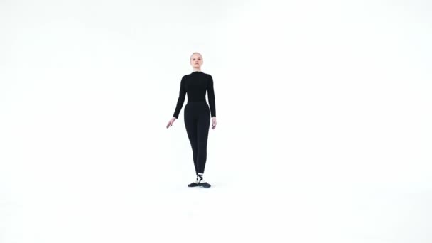 Wanita muda balerina mengangkat kakinya terhadap tubuhnya dan memegangnya di latar belakang putih — Stok Video
