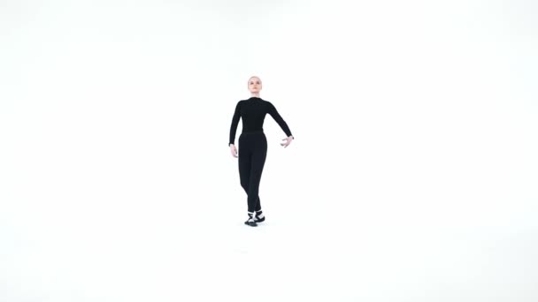 Νεαρή ξανθιά γυναίκα μπαλαρίνα σηκώνει το πόδι της ψηλά και το κρατάει σε λευκό φόντο — Αρχείο Βίντεο