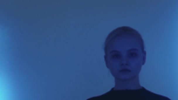 Młoda blondynka ładna kobieta patrząc w aparat w niebieskim oświetleniu — Wideo stockowe