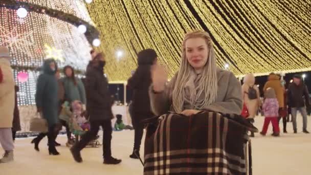 Ung positiv kvinna i rullstol vid jul firar på gatorna - ler och viftar med handen — Stockvideo