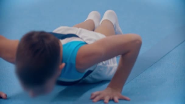 Jimnastik yapan küçük bir çocuk ikiye bölünmüş bir şekilde oturuyor. — Stok video