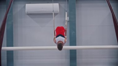 RUSSIA, KAZAN 27-12-20: Spor yüzükleri üzerinde egzersiz yapan küçük jimnastik çocuğu - halkalara sıkıca yaslanıyor ve pozisyonunu koruyor