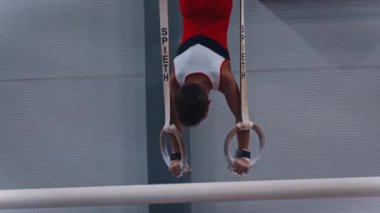 RUSSIA, KAZAN 27-12-20: Spor ringlerinde egzersiz yapan küçük jimnastik çocuğu - halkalara çok yaslanıyor ve pozisyonunu koruyor.