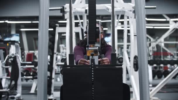 Una mujer afroamericana haciendo ejercicio en un gimnasio - entrenando manos en un equipo de ejercicios con pesas — Vídeos de Stock