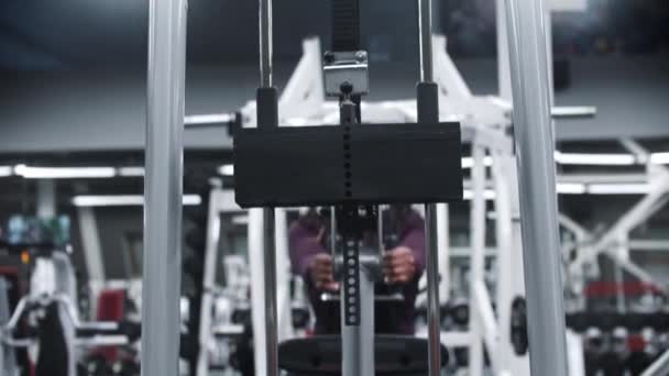 Una mujer negra haciendo ejercicio en un gimnasio - entrenando manos en un equipo de ejercicios con pesas - cámara siguiendo los pesos — Vídeos de Stock