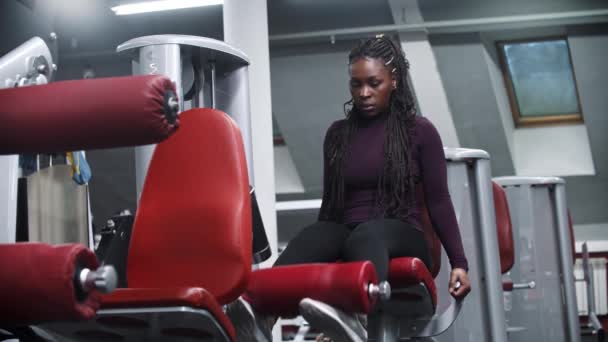Африкано-американская женщина, работающая в тренажерном зале на тренажере - накачивая мышцы ног — стоковое видео