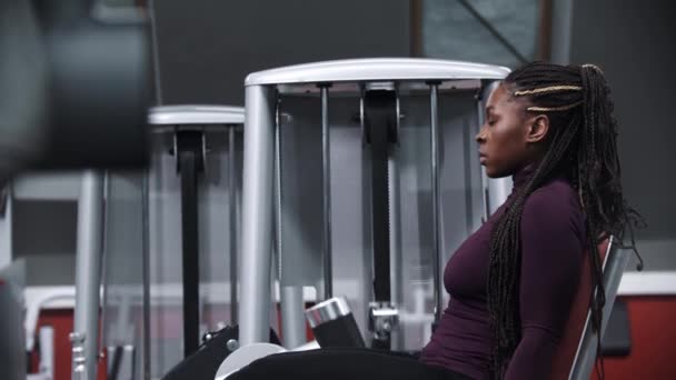 Černá žena s copánky trénuje nohy na cvičebním zařízení — Stock video
