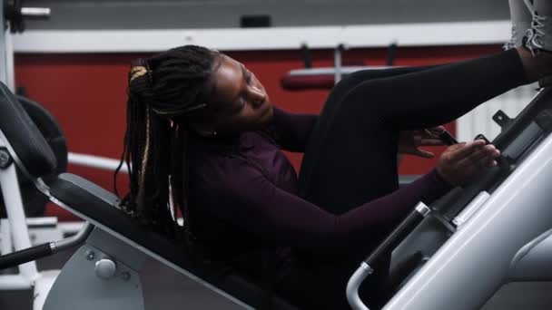 Černá žena s copánky nastavující cvičební pomůcky pro nohy — Stock video