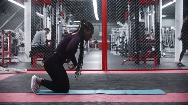 Черная женщина отжимается на коврике для йоги — стоковое видео