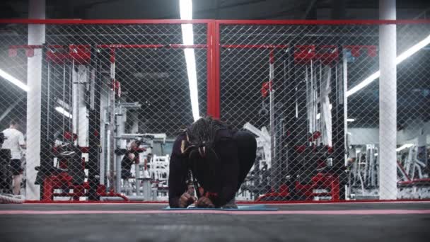 Een Afrikaans-Amerikaanse vrouw staat op van een yoga mat in de sportschool — Stockvideo