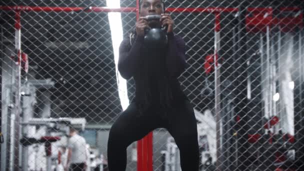 Een Afrikaans-Amerikaanse vrouw kraken met gewicht in een sportschool — Stockvideo