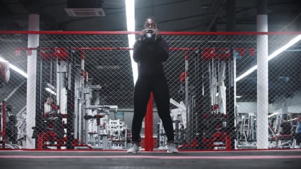 Eine afrikanisch-amerikanische Sportlerin hockt mit Gewicht in einem Fitnessstudio — Stockvideo