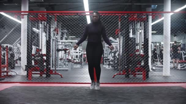 Африкано-американская женщина, прыгающая через веревку в современном спортзале - упражнения на выносливость — стоковое видео