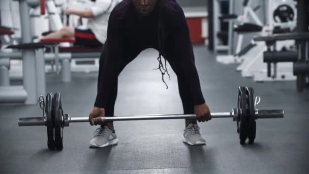 Strong african-american woman pulling up a dumbbell in a gym — Stock Video