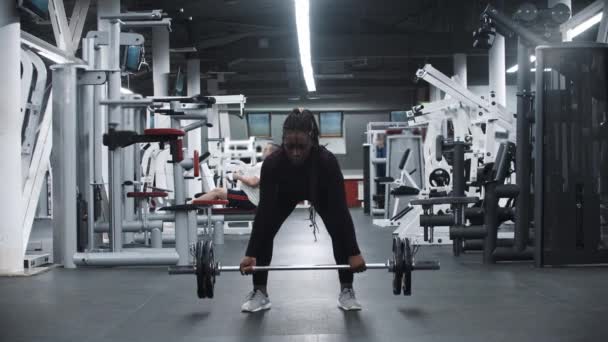 Stark svart kvinna drar upp en hantel i ett gym — Stockvideo