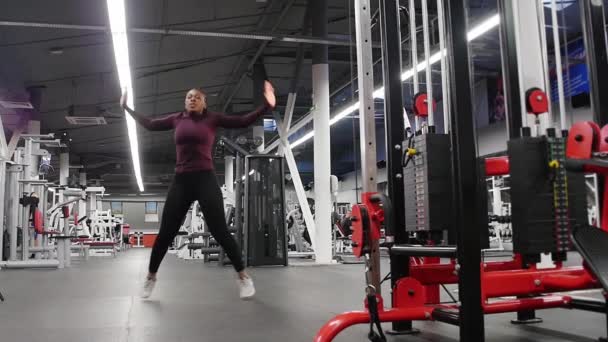 Sport träning - svart kvinna hoppar på en plats i det moderna gymmet — Stockvideo