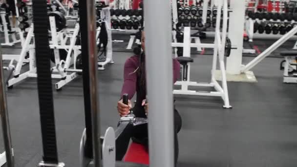 Treinamento de esportes em ambientes fechados - mulher negra com tranças treinando suas mãos em um equipamento de exercício — Vídeo de Stock