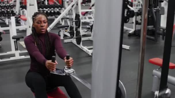 Αθλητική προπόνηση σε εσωτερικούς χώρους - μαύρη γυναίκα με κοτσίδες εκπαιδεύει τα χέρια της σε εξοπλισμό άσκησης και μετά γελάει — Αρχείο Βίντεο