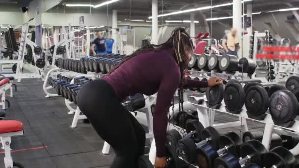 Sportträning - afrikansk-amerikansk kvinna tränar med en hantel i ett modernt gym — Stockvideo