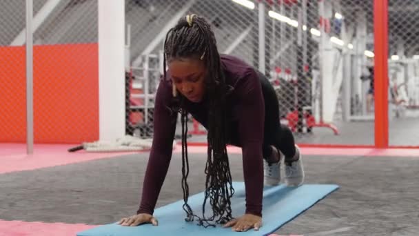 Entrenamiento deportivo - mujer afroamericana haciendo flexiones en la esterilla de yoga en el gimnasio — Vídeos de Stock