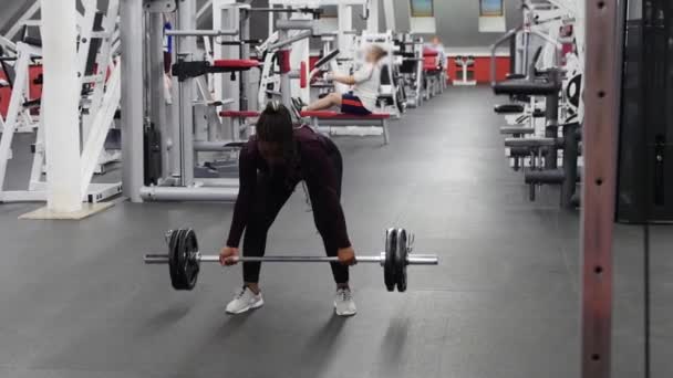 Αθλητισμός στο γυμναστήριο - ισχυρή μαύρη γυναίκα τραβώντας ένα βαράκι σε ένα γυμναστήριο — Αρχείο Βίντεο