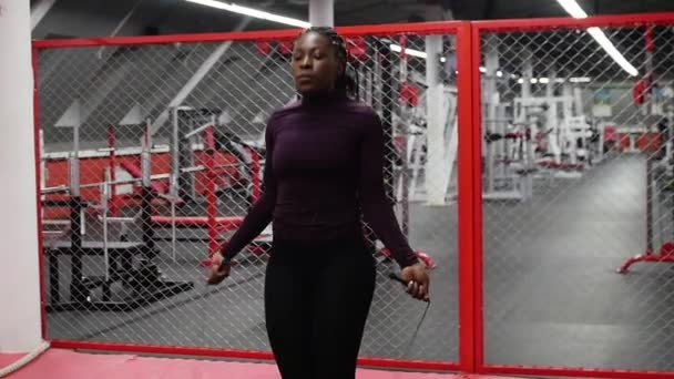 Спорт в тренажерном зале - черная женщина прыгает через веревку - упражнения на выносливость — стоковое видео