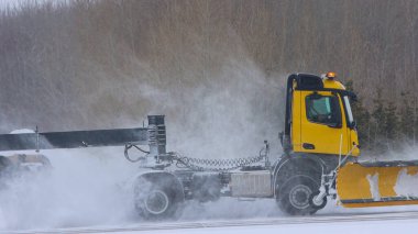 Karlı havaalanında bir kamyon yolu temizliyor.