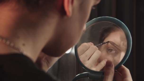 Drag Artist - junger Mann zeichnet neue Augenbrauen vor dem kleinen Spiegel — Stockvideo