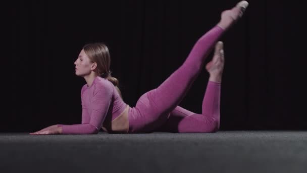 Jovem ginasta do sexo feminino se aquecendo no treinamento dobrando a perna para a cabeça — Vídeo de Stock