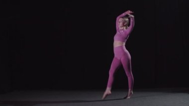 Siyah stüdyoda dans eden güzel sarışın kadın jimnastikçi.