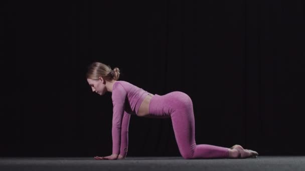 Jeune gymnaste féminine échauffement sur l'entraînement - échauffement et étirement son dos sur le sol — Video