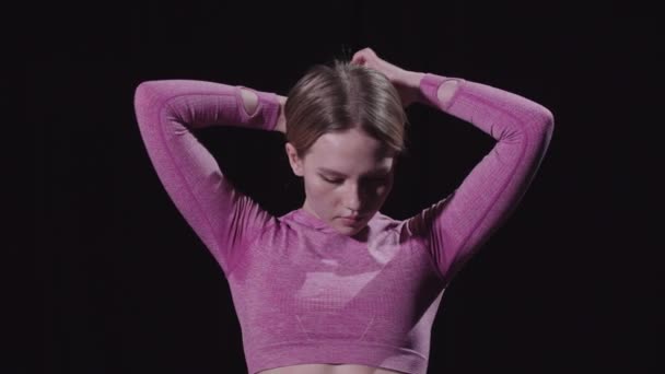 Mladá krásná žena gymnastka dává své vlasy do housky a pak se dívá do kamery — Stock video