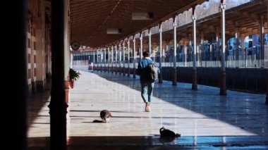 Açık hava tren istasyonunda yürüyen genç bir gezgin.