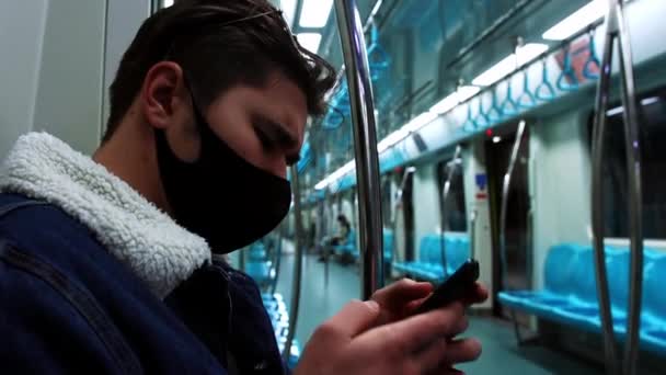 Un jeune homme masqué noir assis dans un train de métro vide — Video