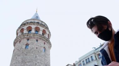 Genç adam Galata Kulesi 'nin yanından geçiyor ve fotoğrafını çekiyor.