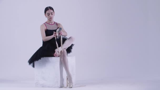 Bailarina joven en vestido negro poniéndose zapatos puntiagudos en el estudio — Vídeo de stock