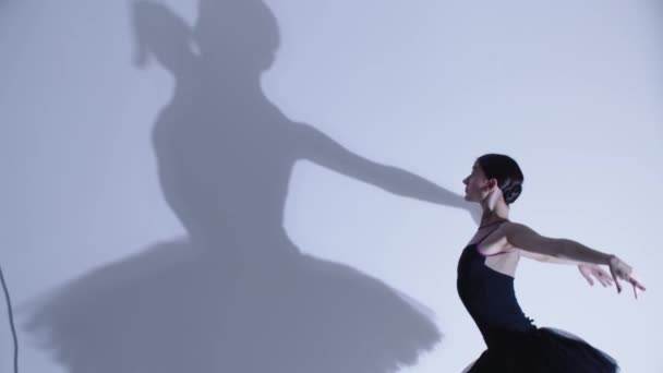 Jovem bailarina em vestido preto dançando - uma grande sombra na parede — Vídeo de Stock