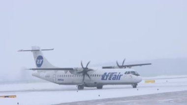 10-02-2021 KAZAN, RUSSIA, Kazan Uluslararası Havaalanı: UTAIR kampanyasından beyaz bir uçak karlı bir pistte dönüş yapıyor