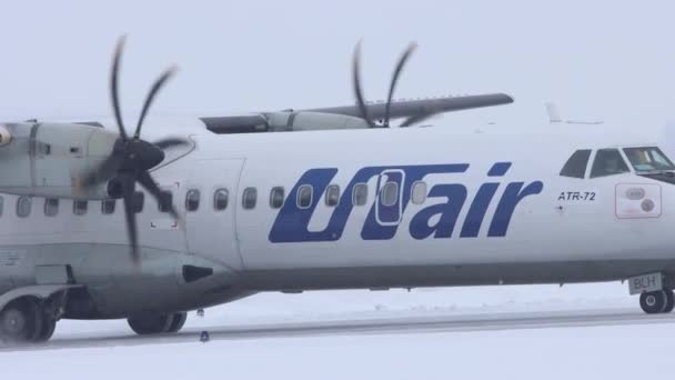 10-02-2021 KAZAN, RUSIA, Aeropuerto Internacional de Kazán: un avión blanco con grandes válvulas de la campaña UTAIR ganando velocidad en una pista nevada — Vídeo de stock