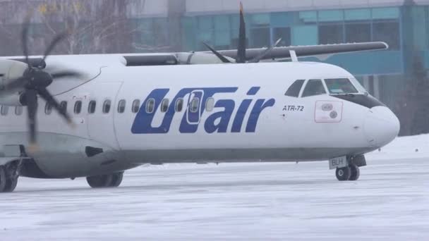 10-02-2021 КАЗАН, РОССИЯ: Белый самолет с большими клапанами от кампании UTAIR движется по снежной взлетно-посадочной полосе — стоковое видео