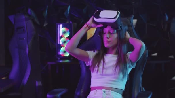 Menina gamer colocando em um óculos VR e olhando ao redor na iluminação de néon — Vídeo de Stock