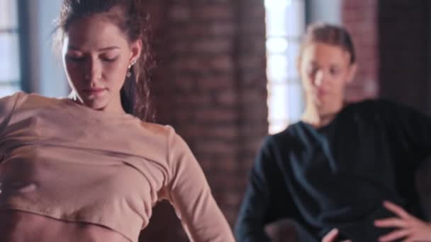 Twee vrouwen warmen hun lichaam samen op in de sportschool - handen aan de taille en doen ronde bewegingen — Stockvideo