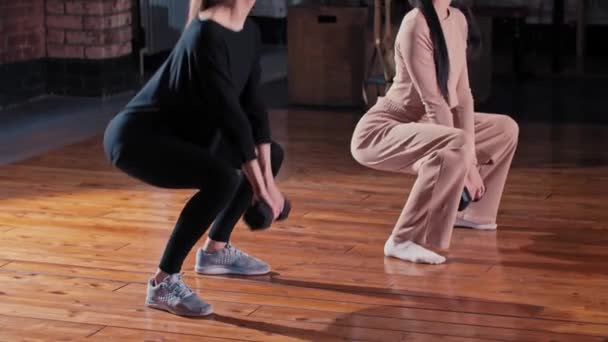 Dvě ženy trénují společně v tělocvičně - dřepí s činkou v ruce — Stock video