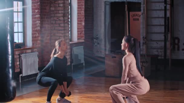 Twee vrouwen samen trainen in de sportschool - hurken met een halter voor elkaar — Stockvideo